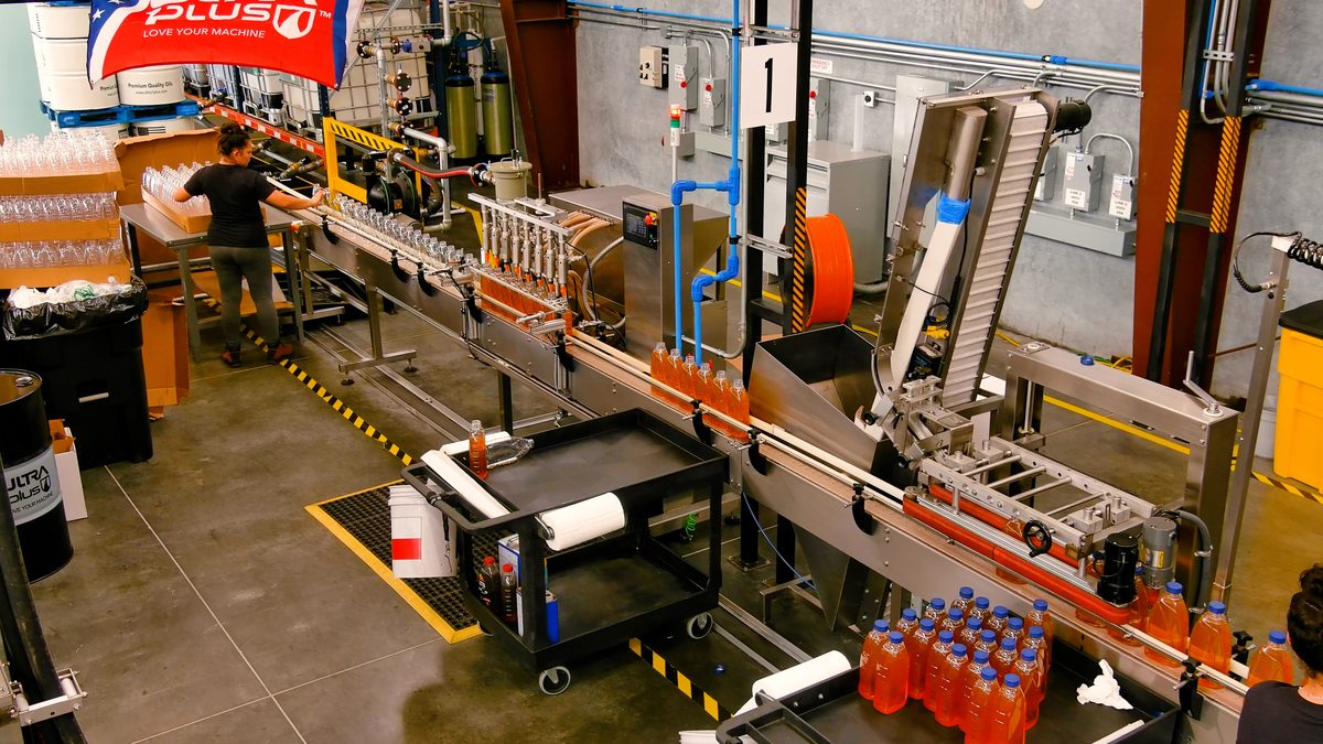 Worker operating automated lubricant bottling production line