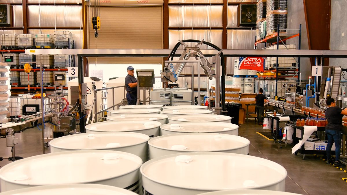 Worker operating drum filling line at U1Dynamics facility